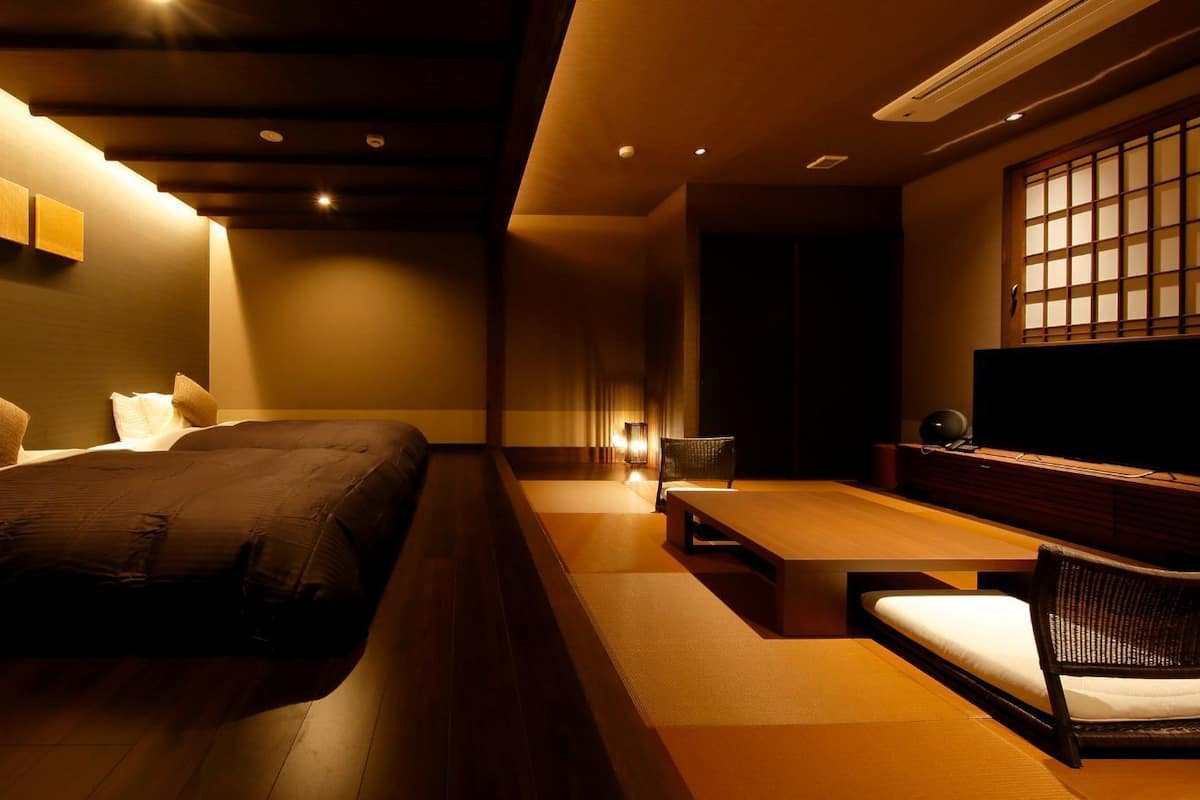 A modern hotel room with a bed, a seating area, and a television.