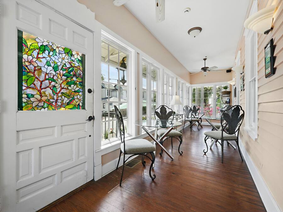A hallway with white doors, a stained glass window, and a view of the outside.