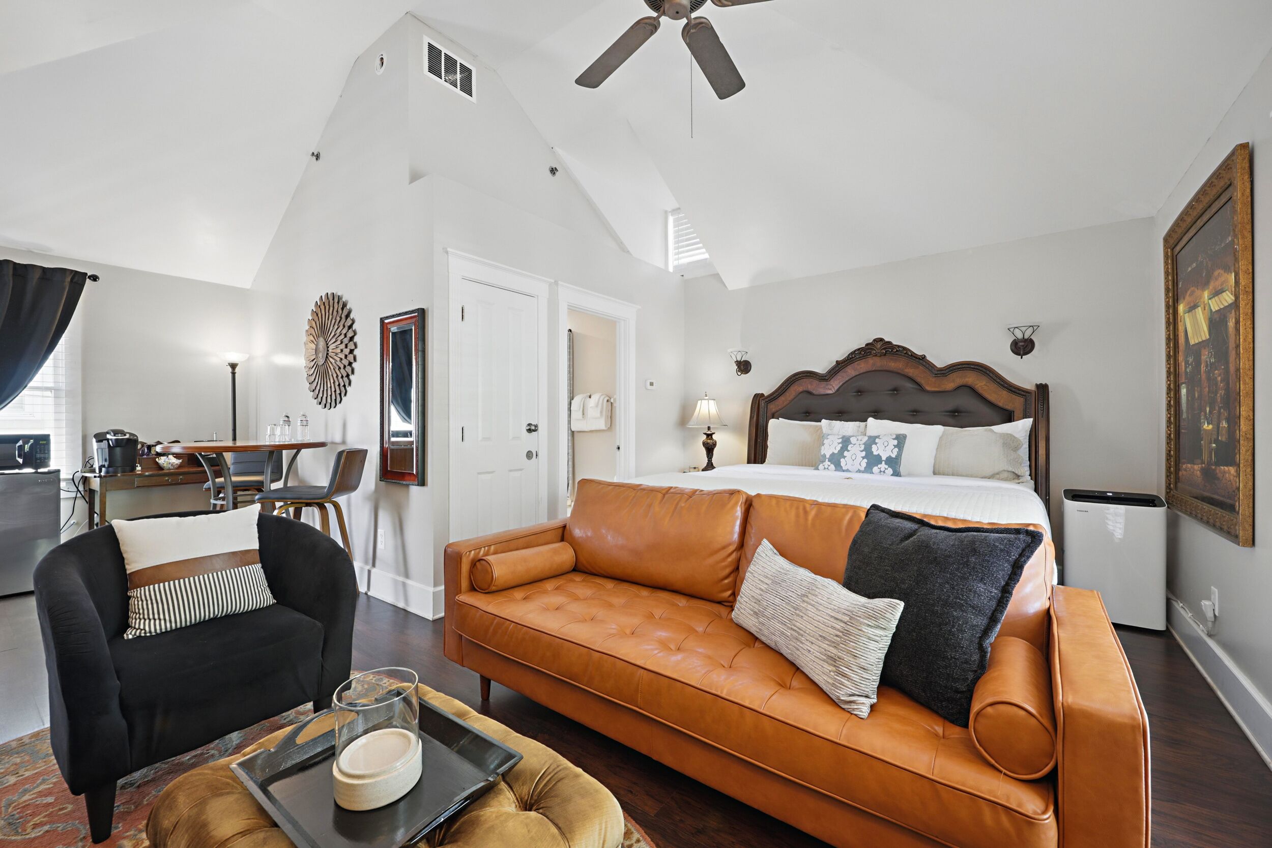 Une chambre avec un grand lit, un canapé, un fauteuil et un coin repas.