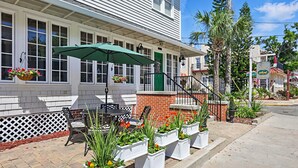 A patio with outdoor seating, a green umbrella, and potted plants. - Carriage Way Centennial (St. Augustine)