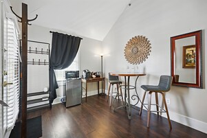 Uma cozinha compacta com micro-ondas, cafeteira e uma pequena mesa com duas cadeiras.