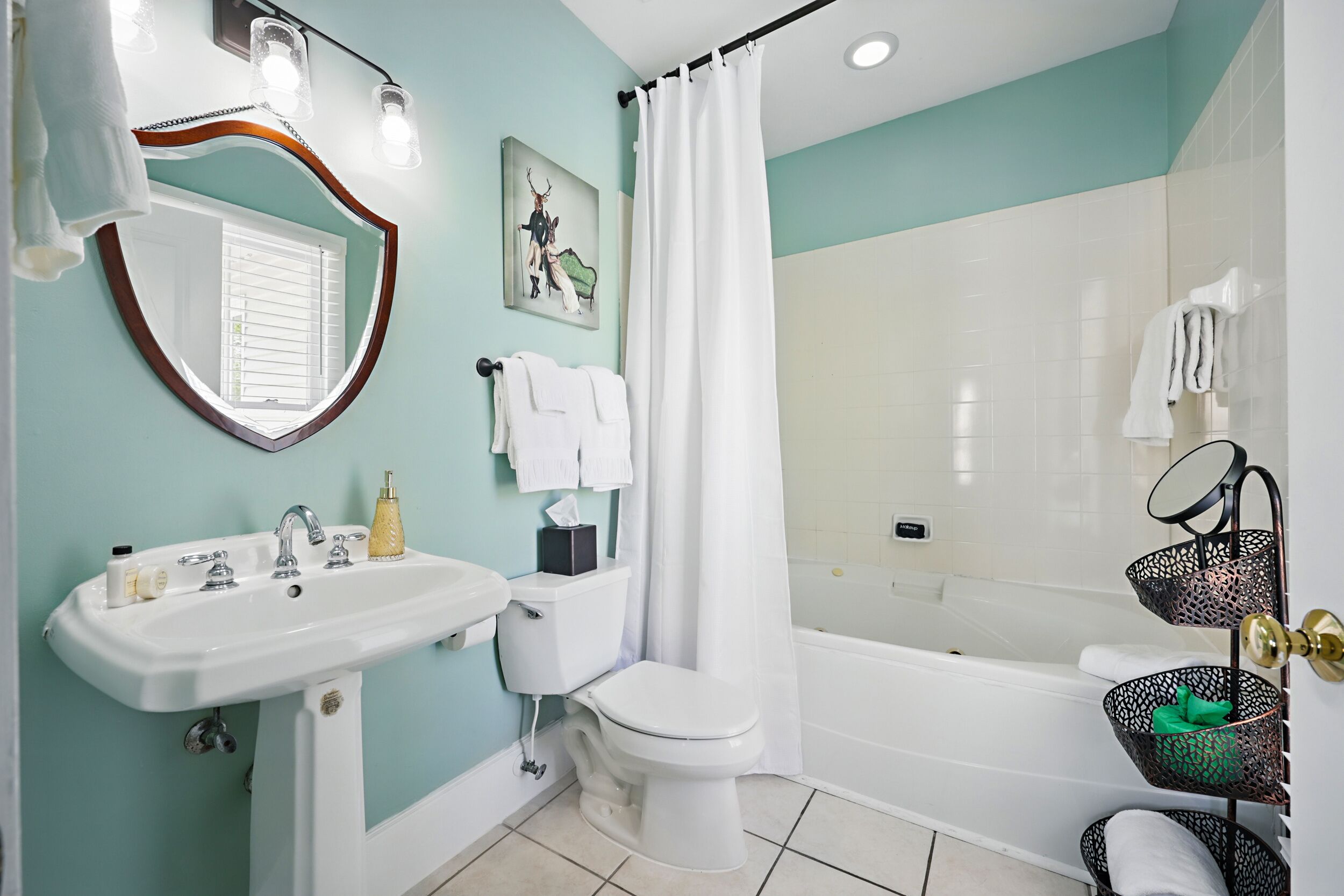 A bathroom with a sink, toilet, and bathtub. There are towels hanging on the wall and a shower curtain.