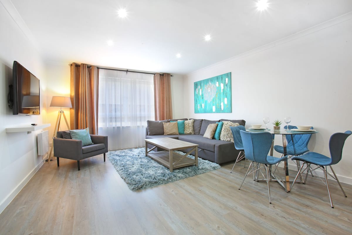 A modern living room with a sofa, coffee table, and dining area.
