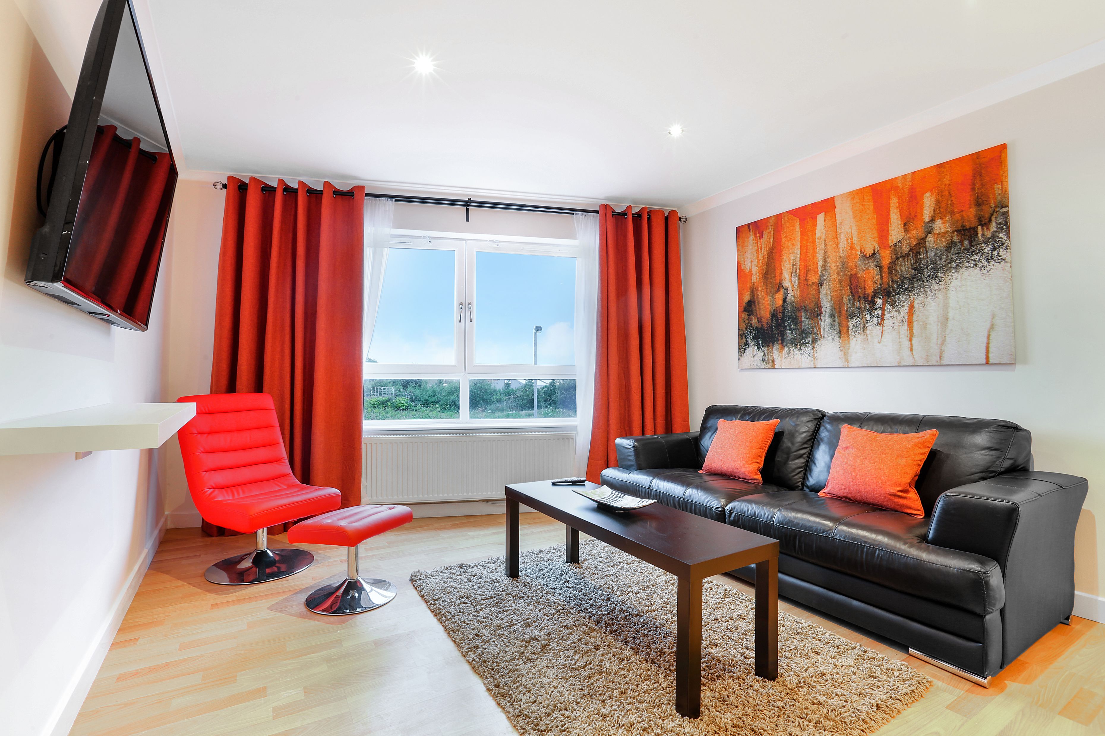 A modern living room with a black leather sofa, red chair, and a coffee table.