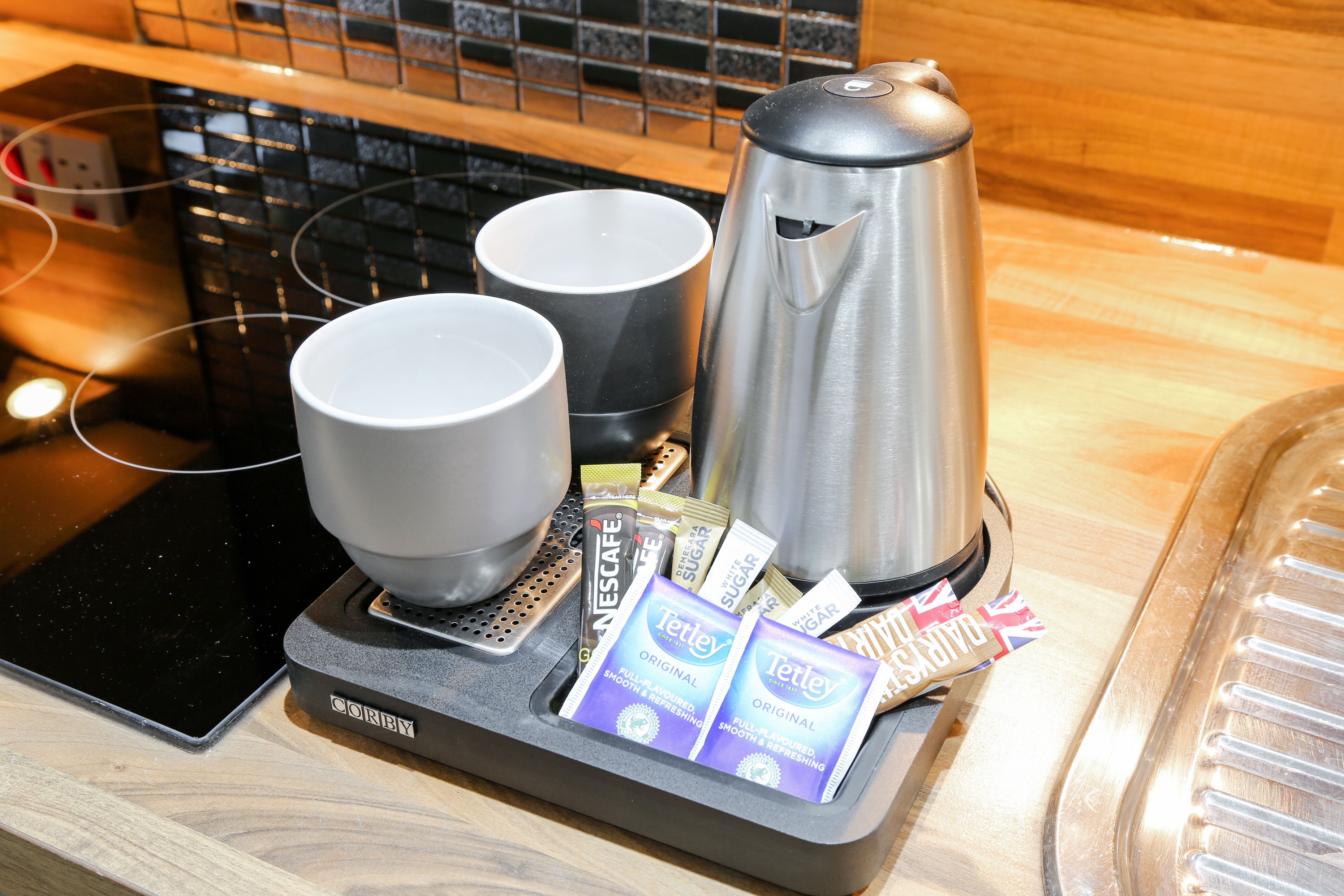 A coffee machine, two cups, and coffee pods on a countertop.