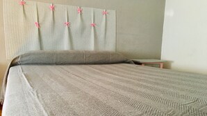 A neatly made bed with a striped bedspread and a herringbone pillow. - Nuevo Tropical (Motril)