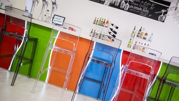 A bar area with colorful stools and a variety of bottles on shelves. - Nuevo Tropical (Motril)