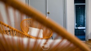 A wicker chair in a room with a door leading to a bathroom with a tiled shower. - Nuevo Tropical (Motril)