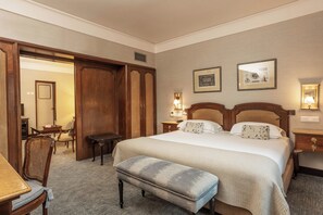 A hotel room with a large bed, a wooden bench, a desk, and a chair. There are two wall-mounted lamps and a framed picture on the wall. - Hotel Lisboa Plaza (Lisbon)