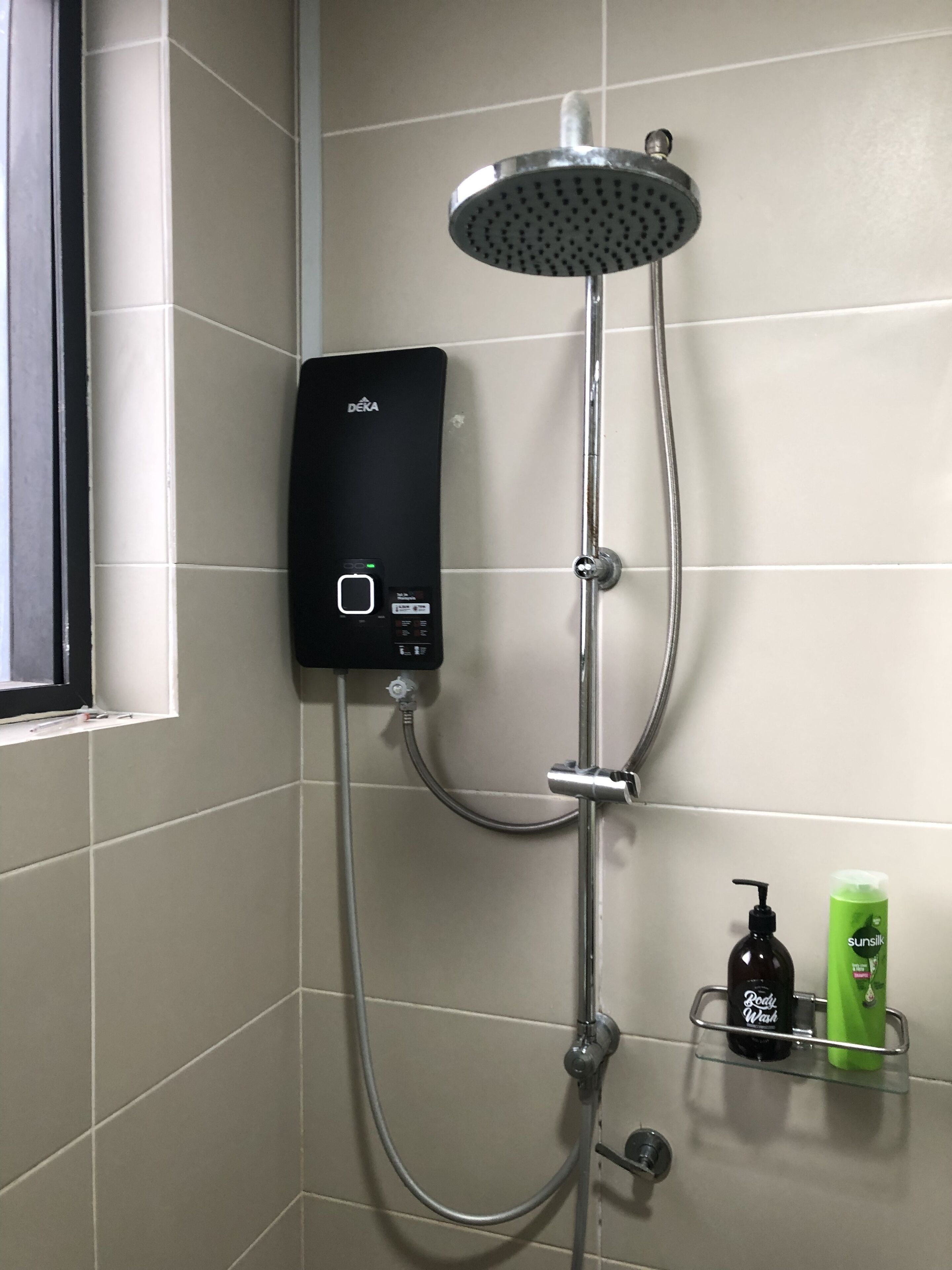 Eine moderne Dusche mit Bedienfeld, Duschbrause und Ablage für Toilettenartikel.