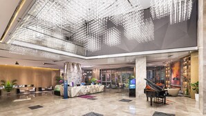 A spacious lobby with a reception desk, seating area, and a grand piano.