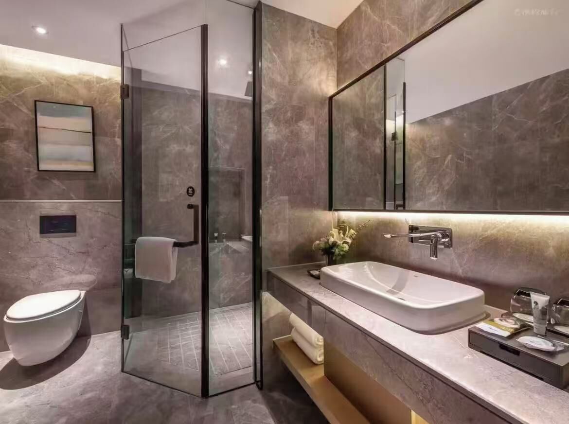 Un baño moderno con cabina de ducha de vidrio, un lavamanos blanco y un espejo grande.