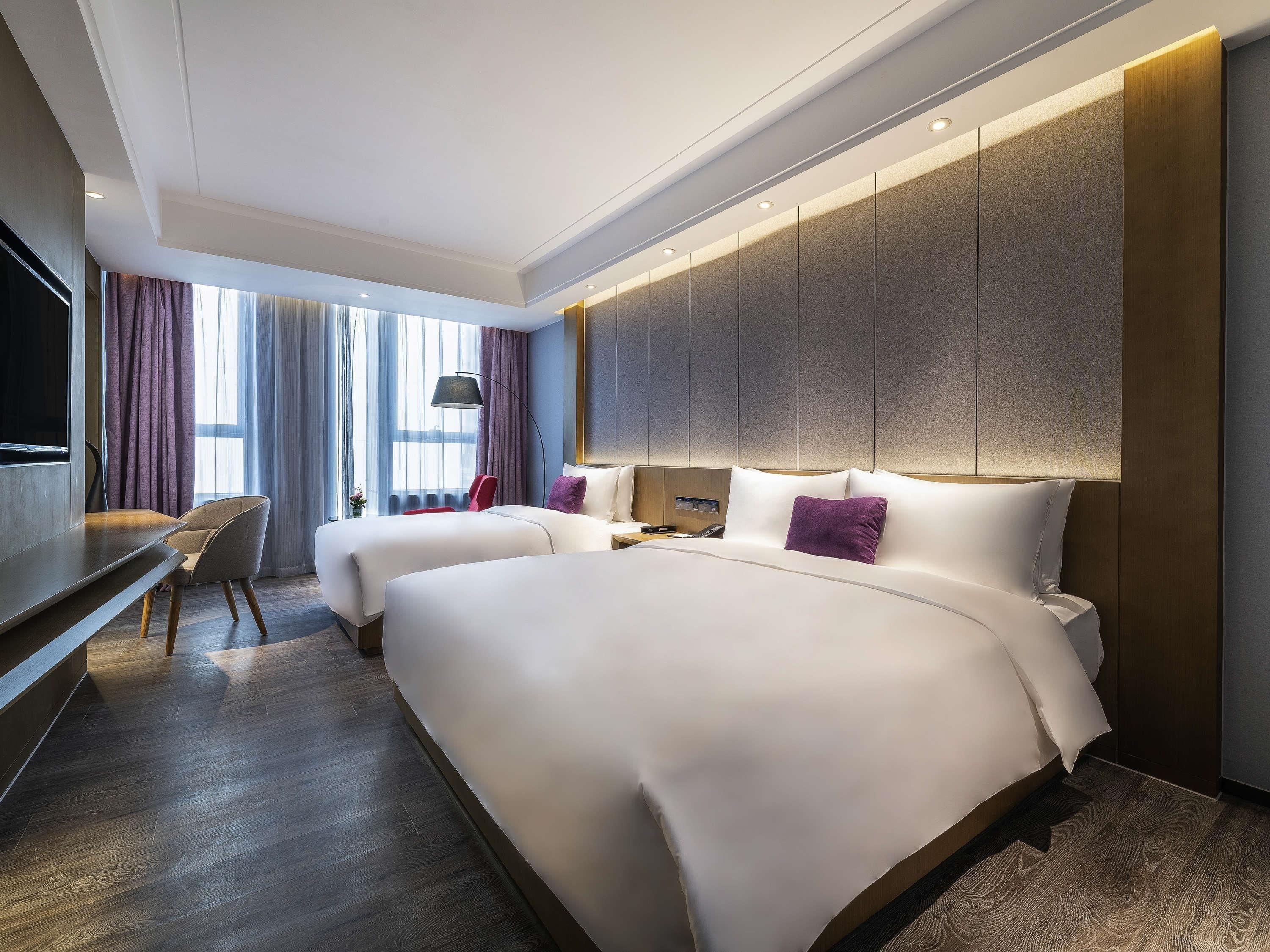 Quarto de hotel com duas camas, uma escrivaninha e uma televisão.