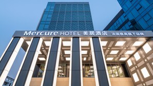 The exterior of the Mercure Hotel with a modern glass facade and a sign indicating it is a hotel. - Mercure Kunshan MIXC Hi-tech (Suzhou)