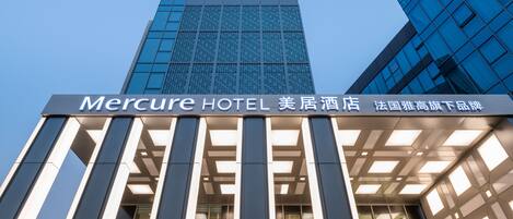El exterior del Hotel Mercure, con una fachada de vidrio moderna y un letrero que indica que es un hotel.