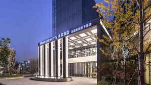 A hotel with a modern facade, a prominent entrance, and a clear sky.