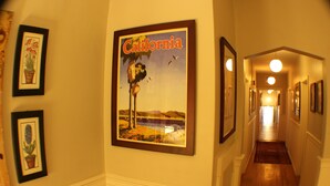 A hallway with framed pictures on the walls, including a prominent California poster. - San Anselmo Inn (San Anselmo)