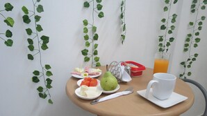 Una mesa redonda pequeña con alimentos para el desayuno, como una pera, un plátano y sandía, un recipiente rojo y una taza blanca.