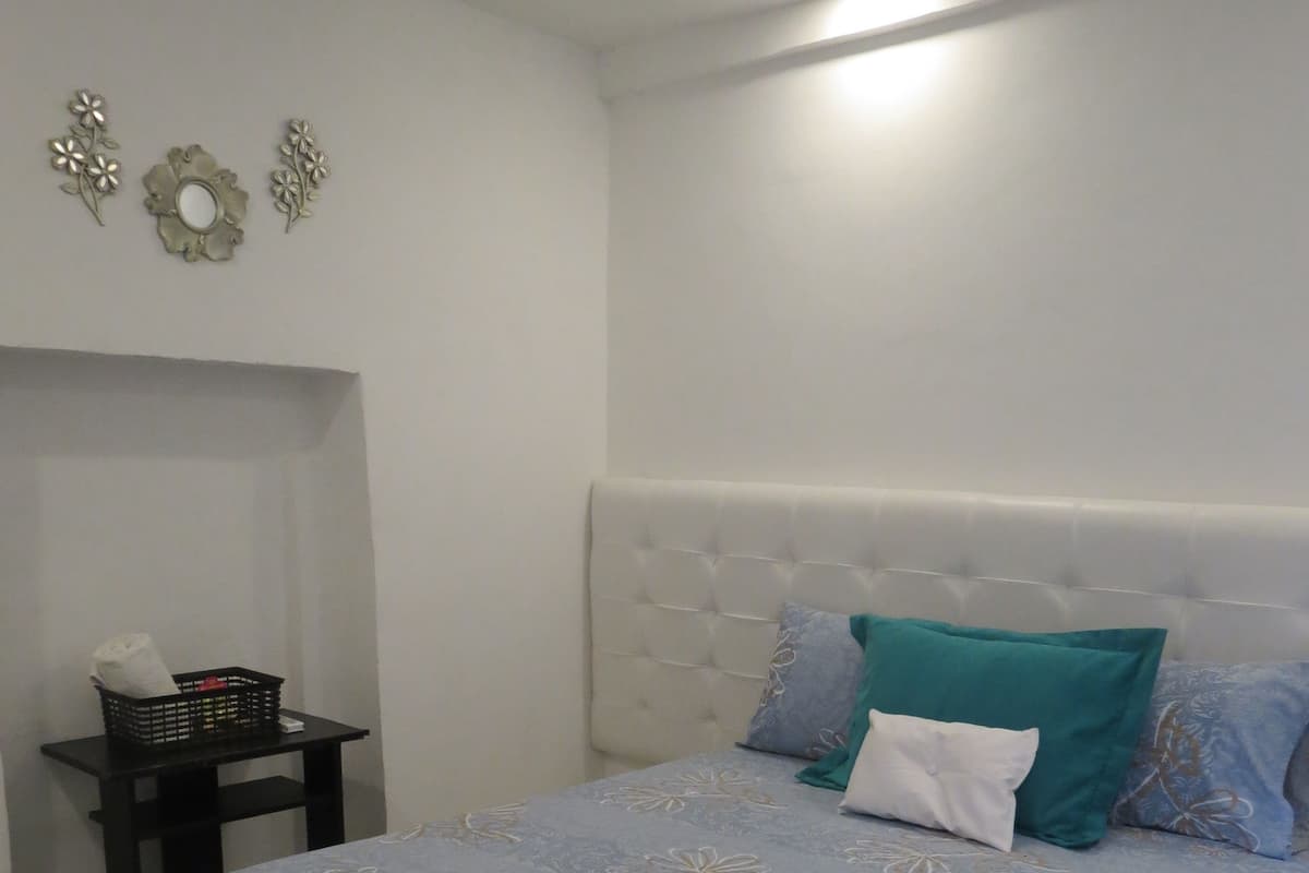 A bedroom with a bed, a nightstand, and wall decorations.