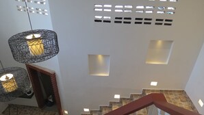 Una escalera con suelo de piedra y barandilla roja, que lleva a una plataforma con pared blanca y chimenea de ladrillo.