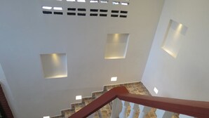 Eine Treppe mit roter Handlauf, weißen Spindeln und einem steinbelagten Boden.