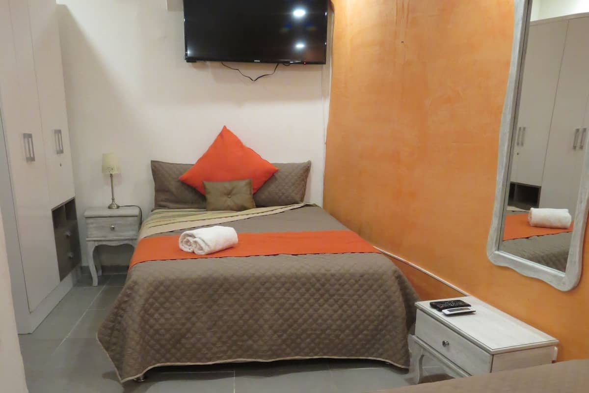 A bedroom with two beds, a TV mounted on the wall, and a mirror on the wall.
