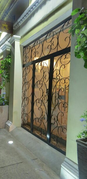 A building entrance with ornate metal gates and a potted plant on the right. - Casa San Luis Hotel (Cartagena)