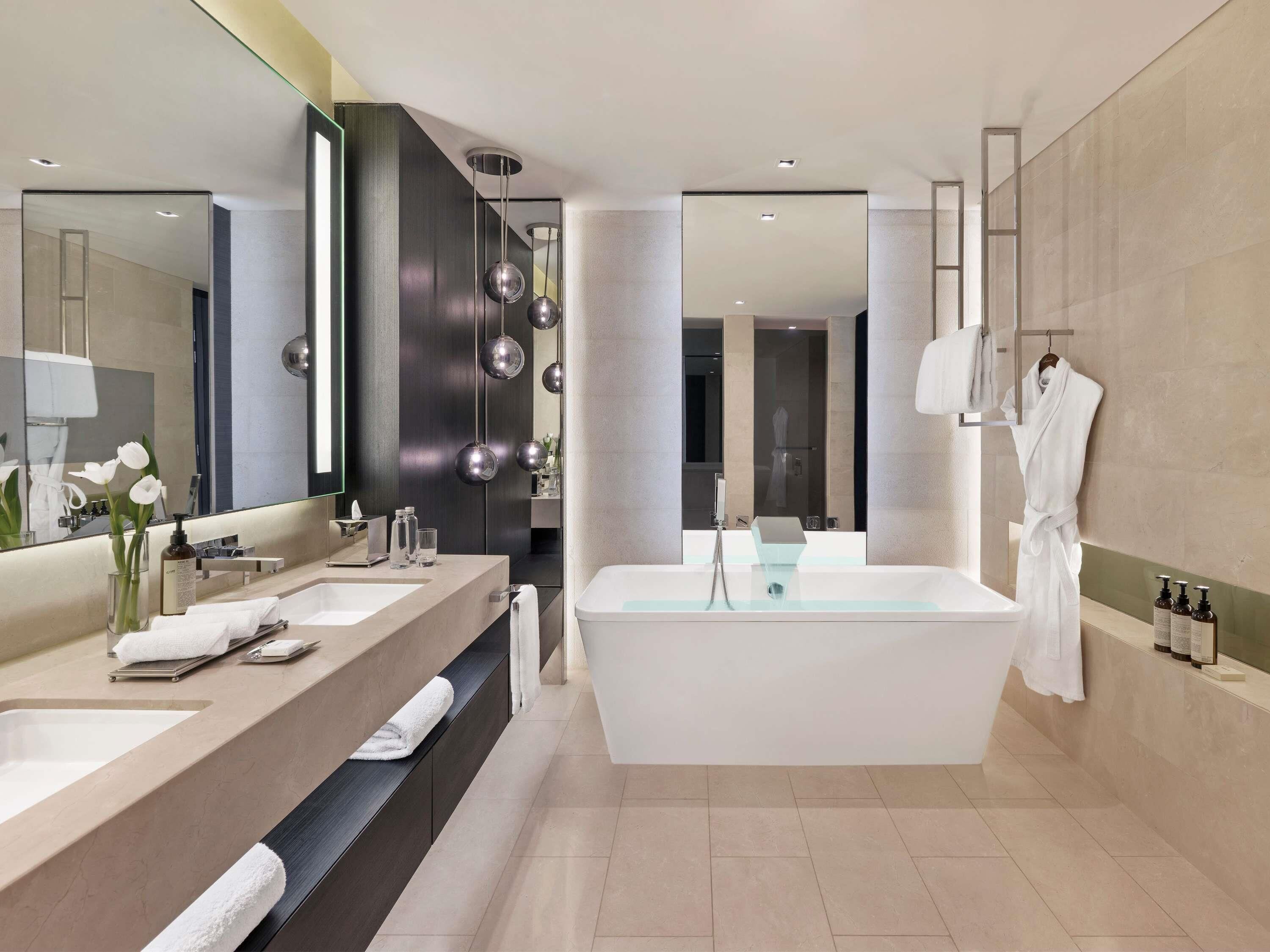 Ein modernes Badezimmer mit einer großen Badewanne, zwei Waschbecken, einem Waschtisch und einem Spiegel.