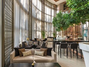 A spacious lounge area with a sofa, chairs, a dining table, and a large indoor tree. - Fairmont Riyadh (Riyadh)