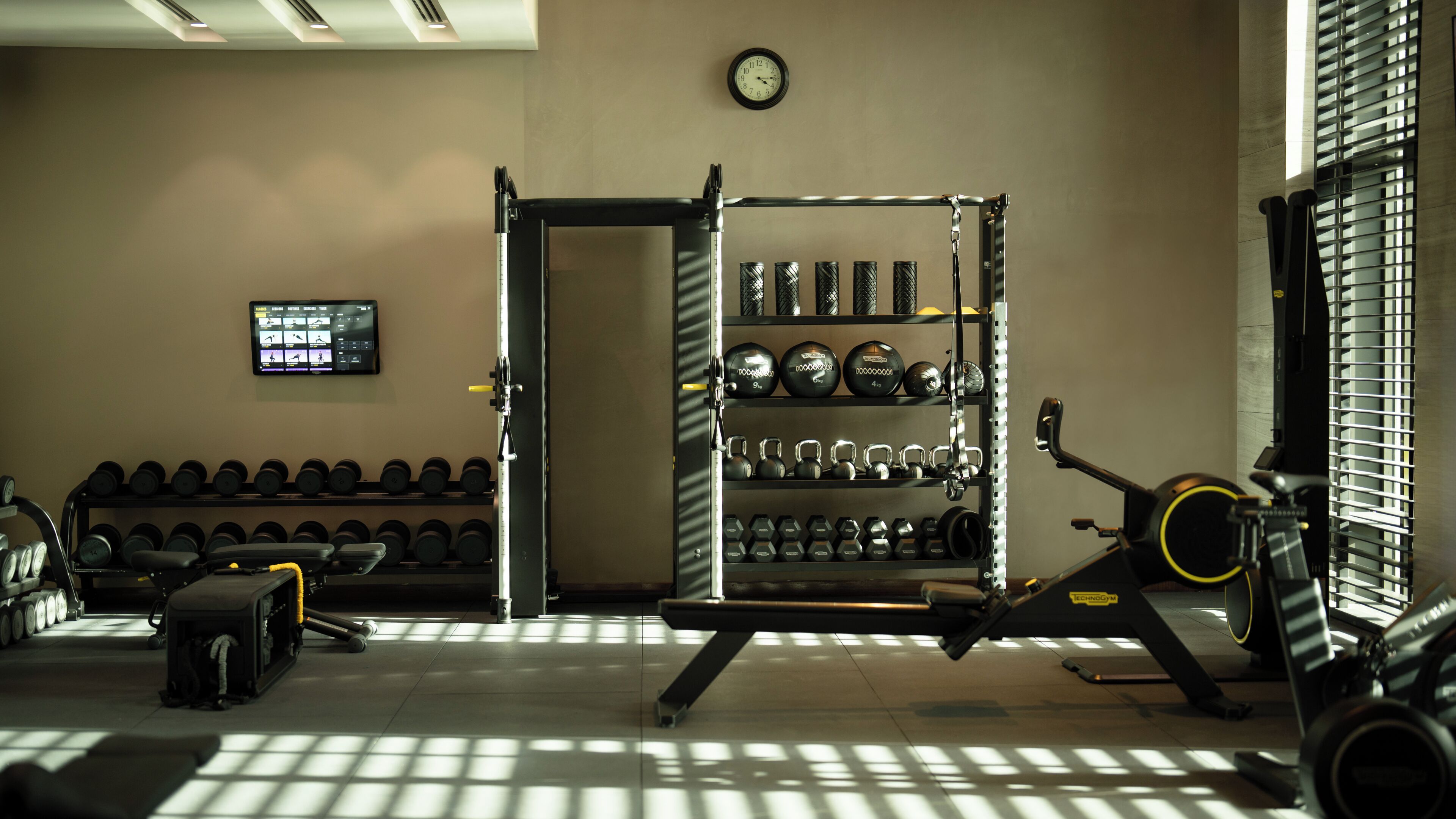 A gym with weightlifting equipment, dumbbells, and a treadmill.