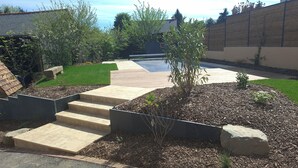 A landscaped garden with a pool, steps leading to a patio, and a wooden fence. - La Peuterne (Mouazé)