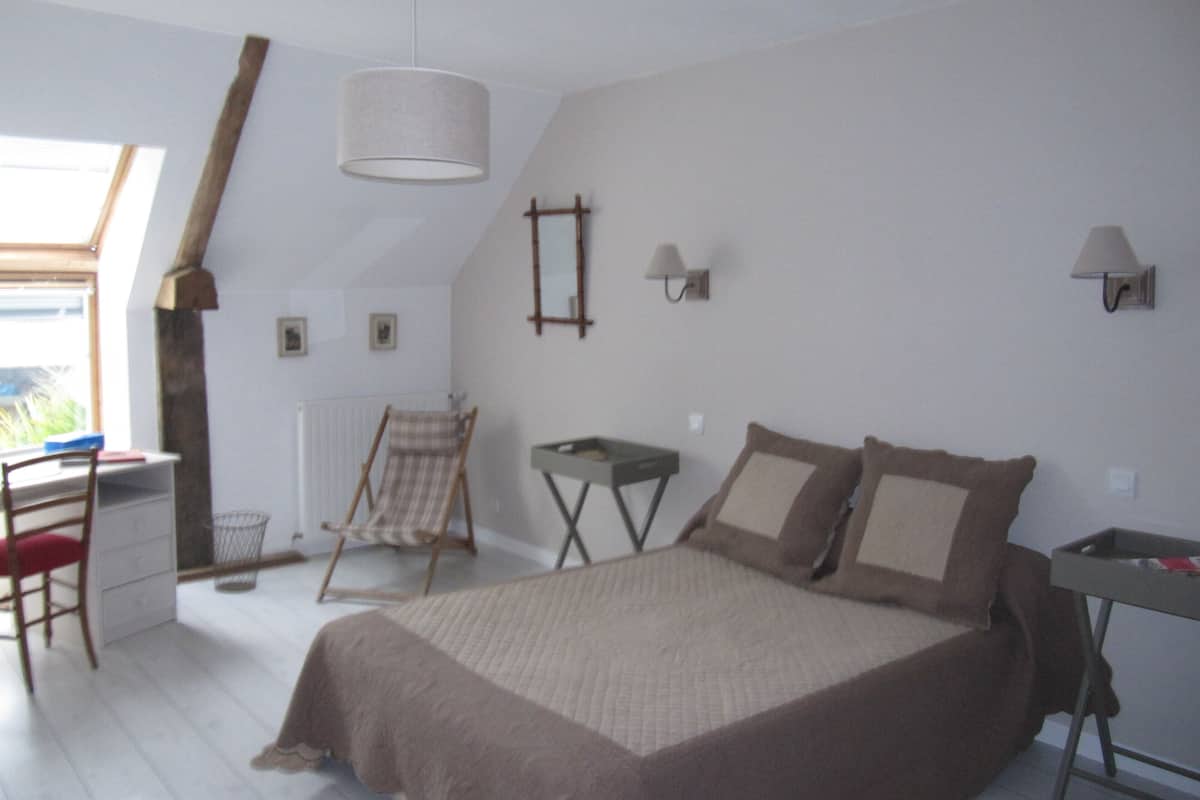 A bedroom with a bed, a chair, a desk, and a window.