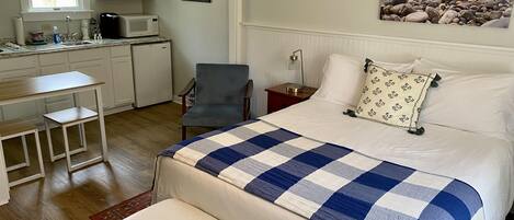 Une chambre à coucher avec un lit, un bureau, une chaise, une table de chevet et un tableau accroché au mur.