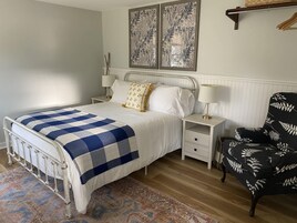 A bedroom with a bed, bedside tables, a chair, and two wall-mounted paintings.