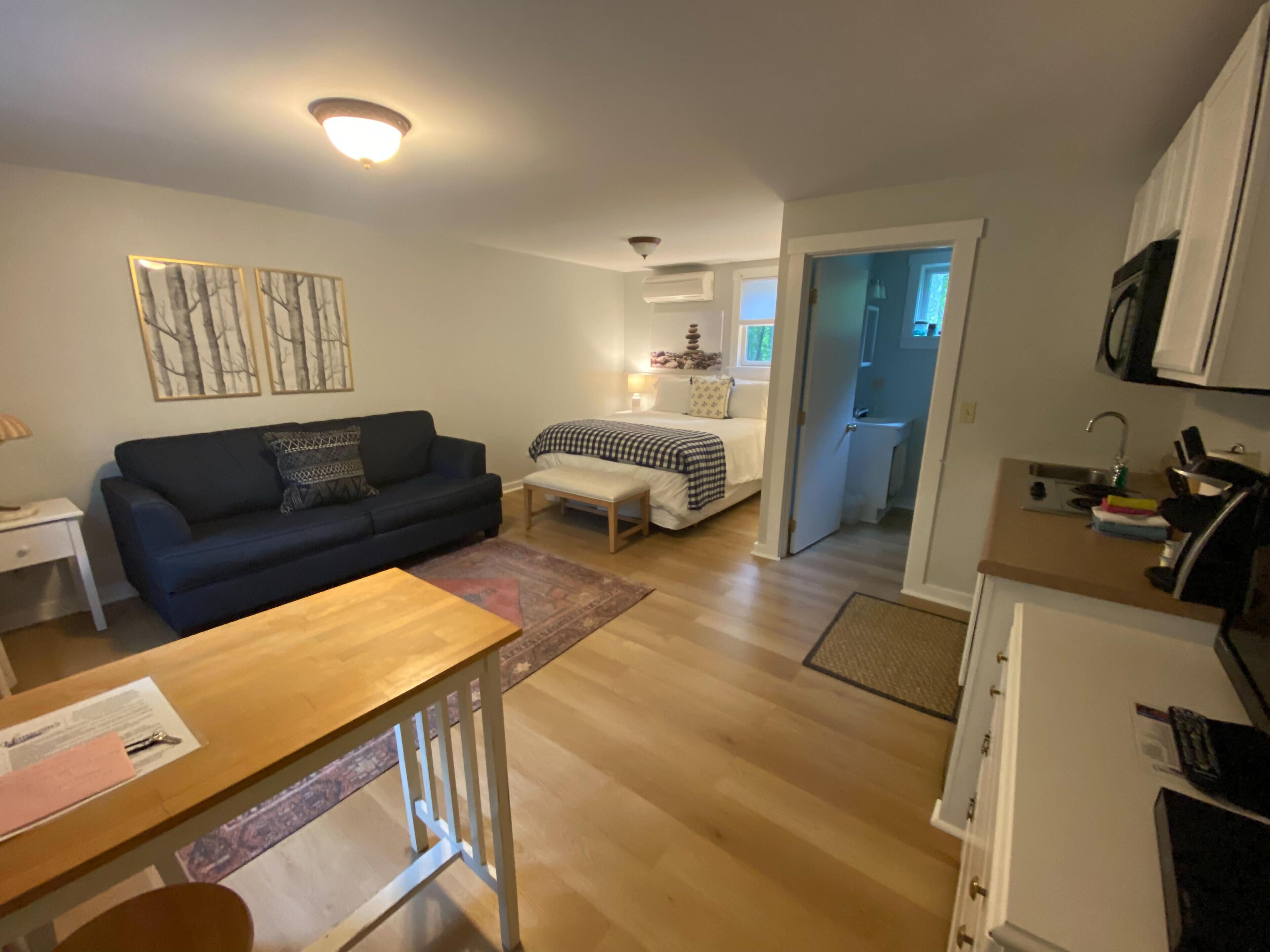 Een knus woongedeelte met een bank, een eettafel, een bed en een kitchenette.