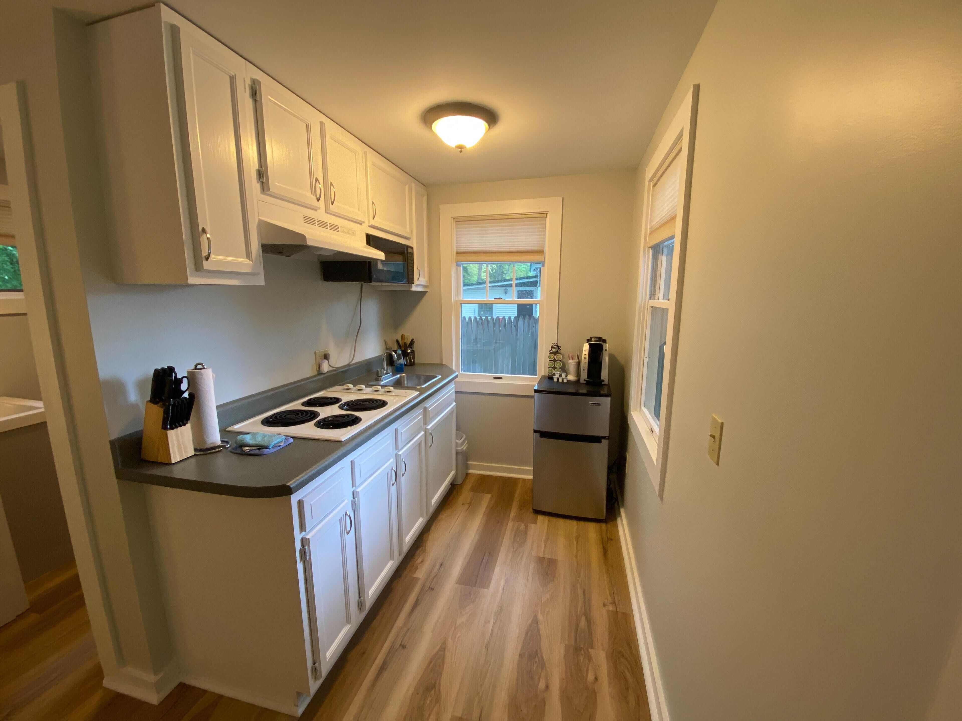 A compact kitchen with white cabinets, a built-in stove, and a small refrigerator.