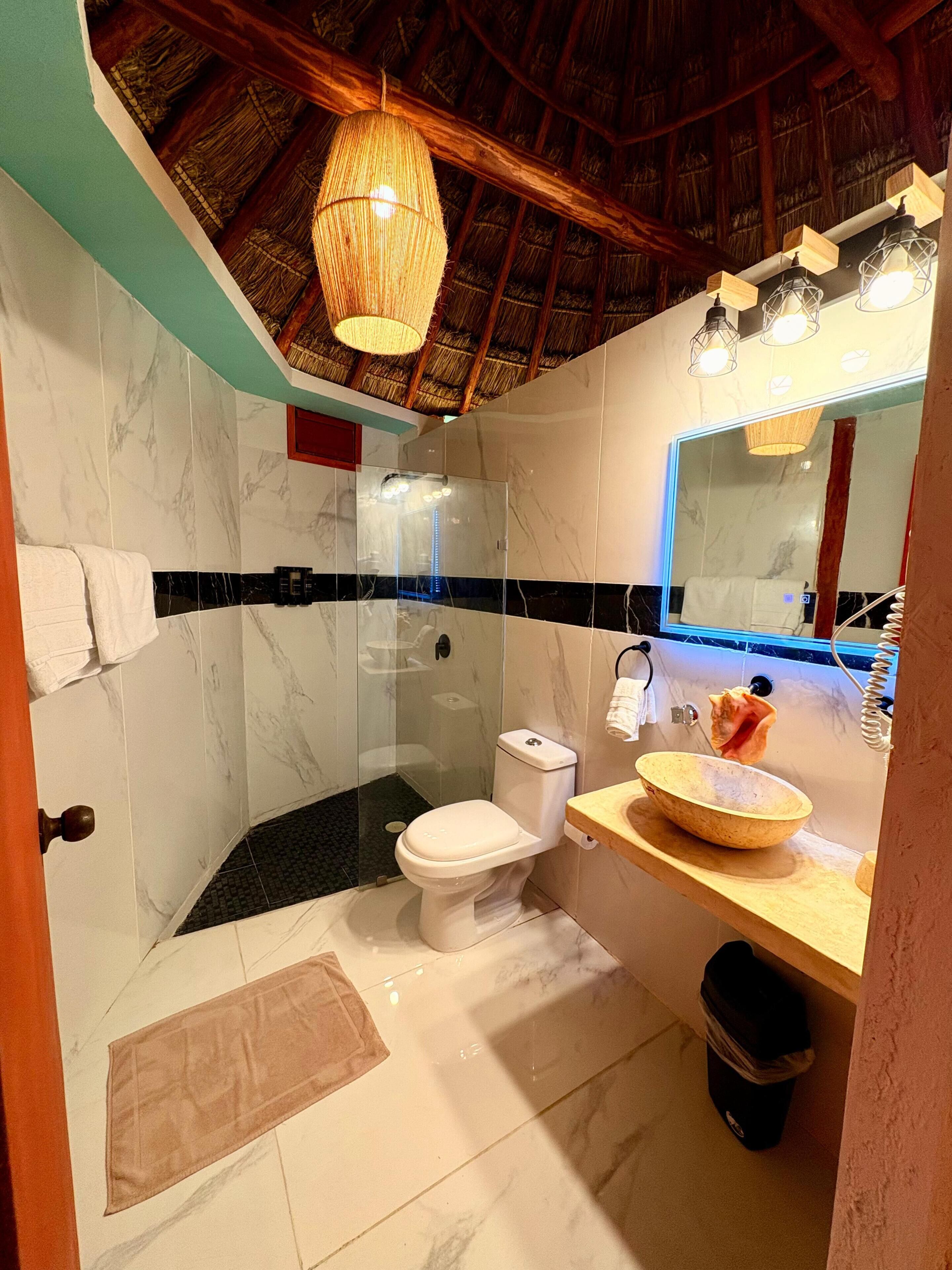 Un baño con ducha vidriada, inodoro, lavabo y espejo.
