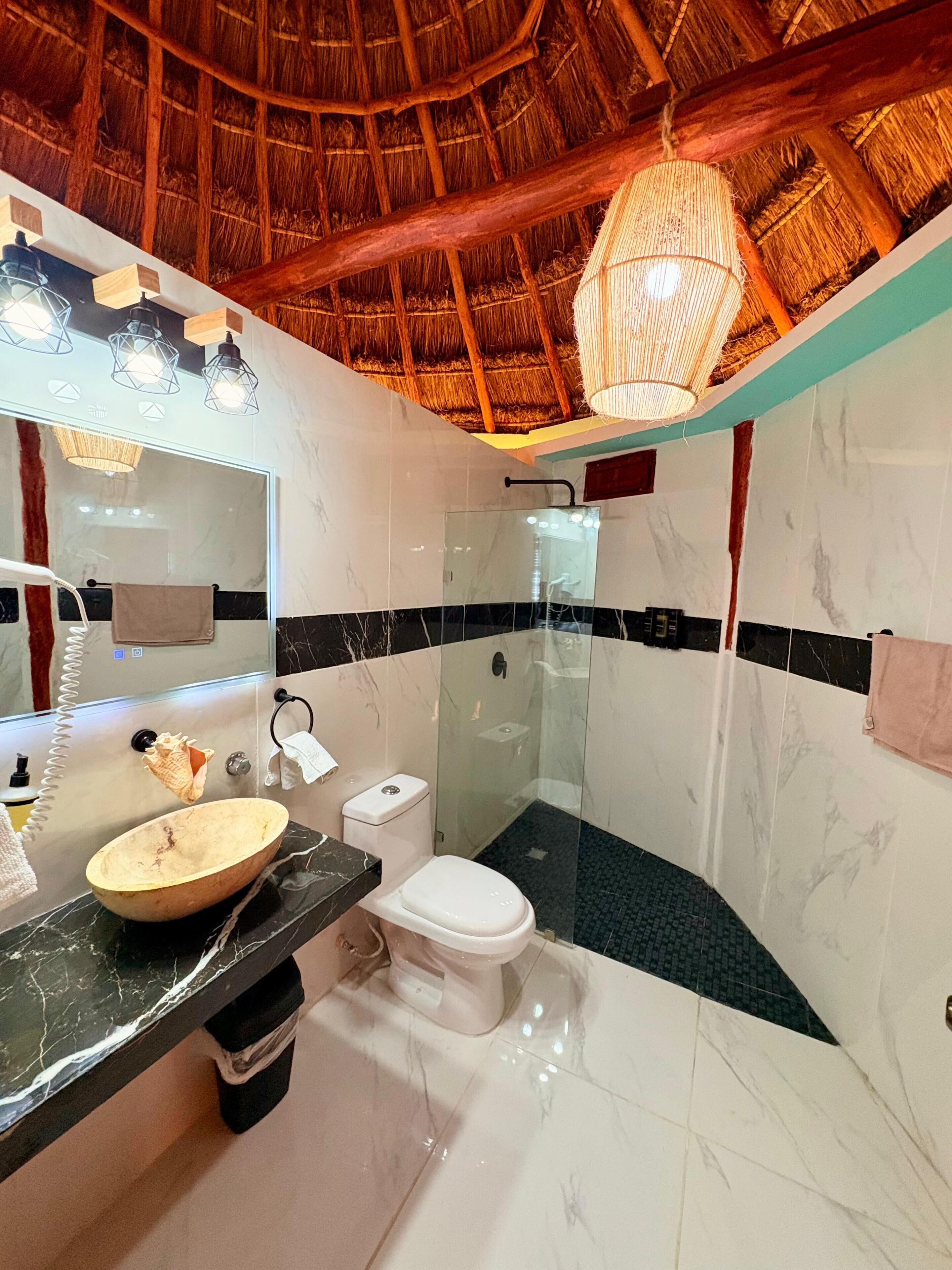 A bathroom with a marble sink, a toilet, and a glass-enclosed shower.