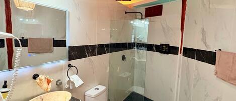 A bathroom with a marble sink, a toilet, and a glass-enclosed shower.