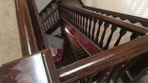 Una escalera de madera con barandilla, peldaños alfombrados y una silla roja al final.