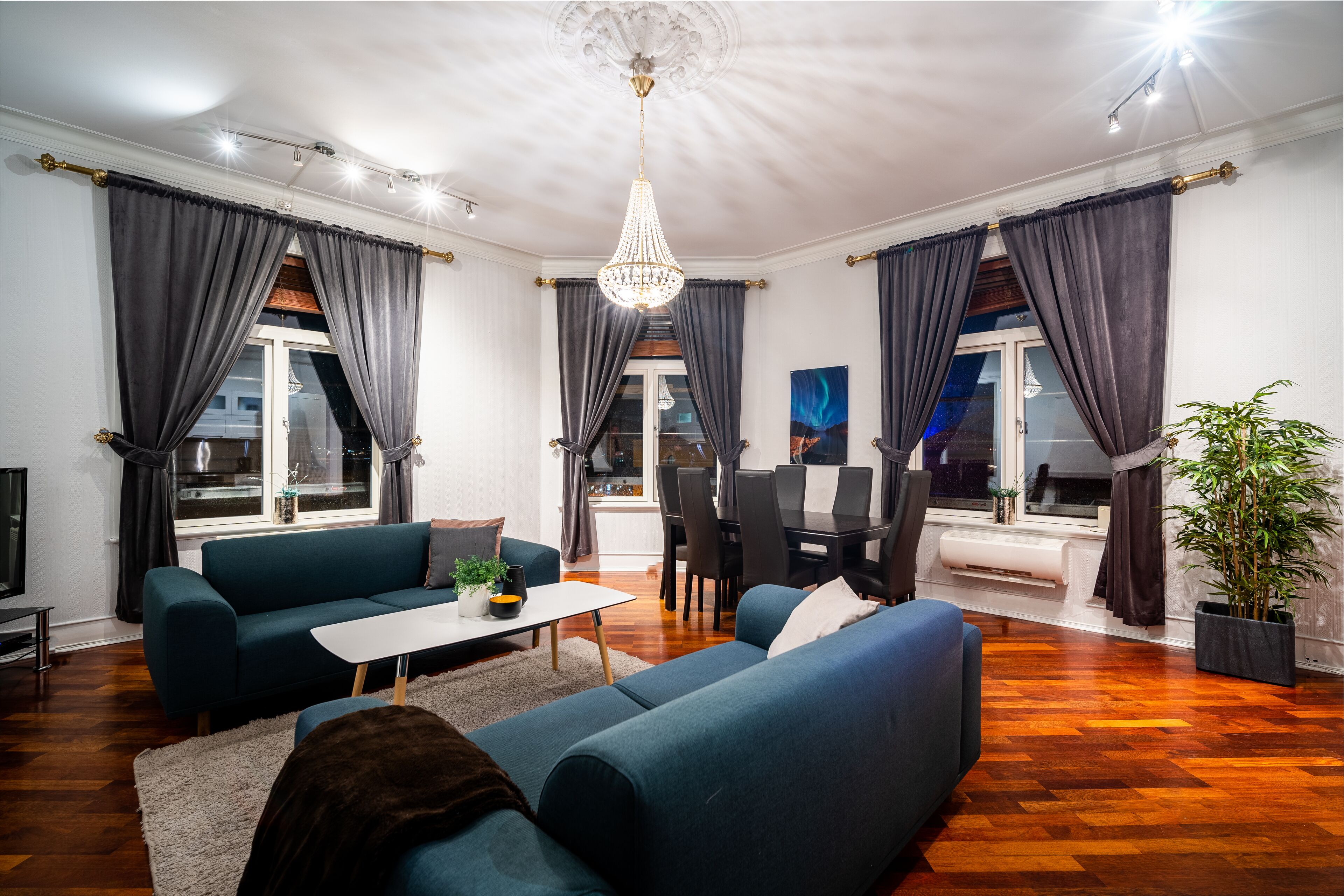 Ein modernes Wohnzimmer mit einem blauen Sofa, einem weißen Couchtisch und einer Chandelüster.