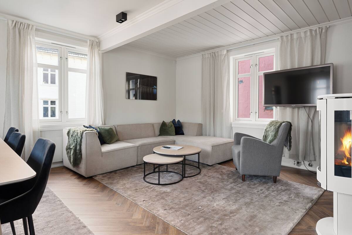 A modern living room with a sofa, armchair, coffee table, and fireplace.