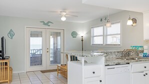 A kitchen with white cabinets, a granite countertop, and a built-in dishwasher. - Gulf Front, Pet Friendly, N. Cape San Blas with Screened Deck ~ Whataday (Cape San Blas)