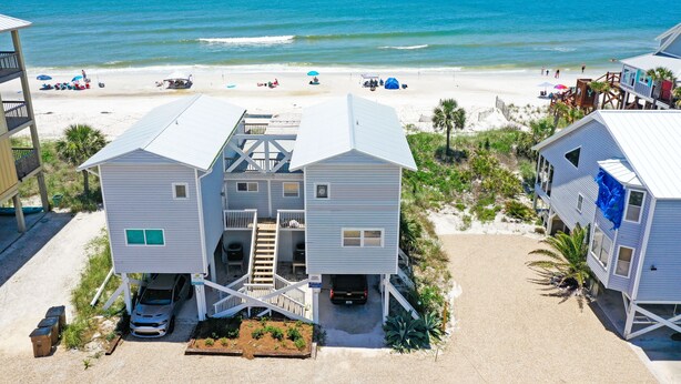 A beachfront property with a two-story house, a covered carport, and a sandy beach in the background. - Gulf Front, Pet Friendly, N. Cape San Blas with Screened Deck ~ Whataday (Cape San Blas)