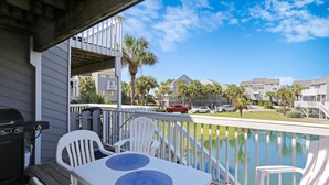 A deck with a table and chairs, overlooking a swimming pool and a residential area. - Barrier Dunes, Close to Beach (Cape San Blas)