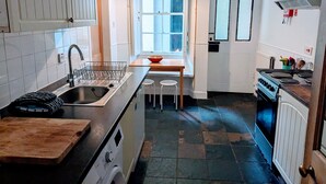 Pieni, käytännöllinen keittiö, jossa on pesuallas, liesi ja ikkuna.