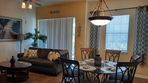 A dining area with a round glass table, black chairs, and a chandelier.