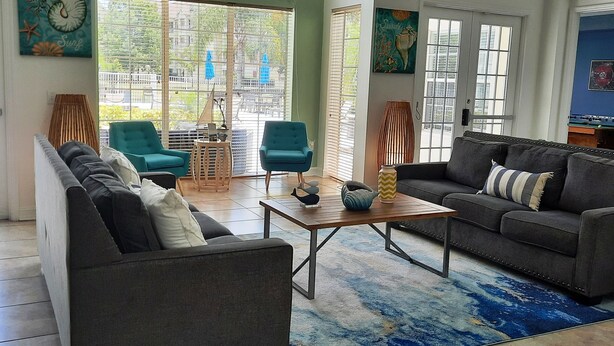 A spacious living area with two sofas, a coffee table, and a view of the outside through large windows.