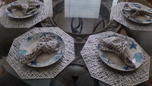 A round glass table with six plates and napkins, each with a giraffe pattern, set for a meal.