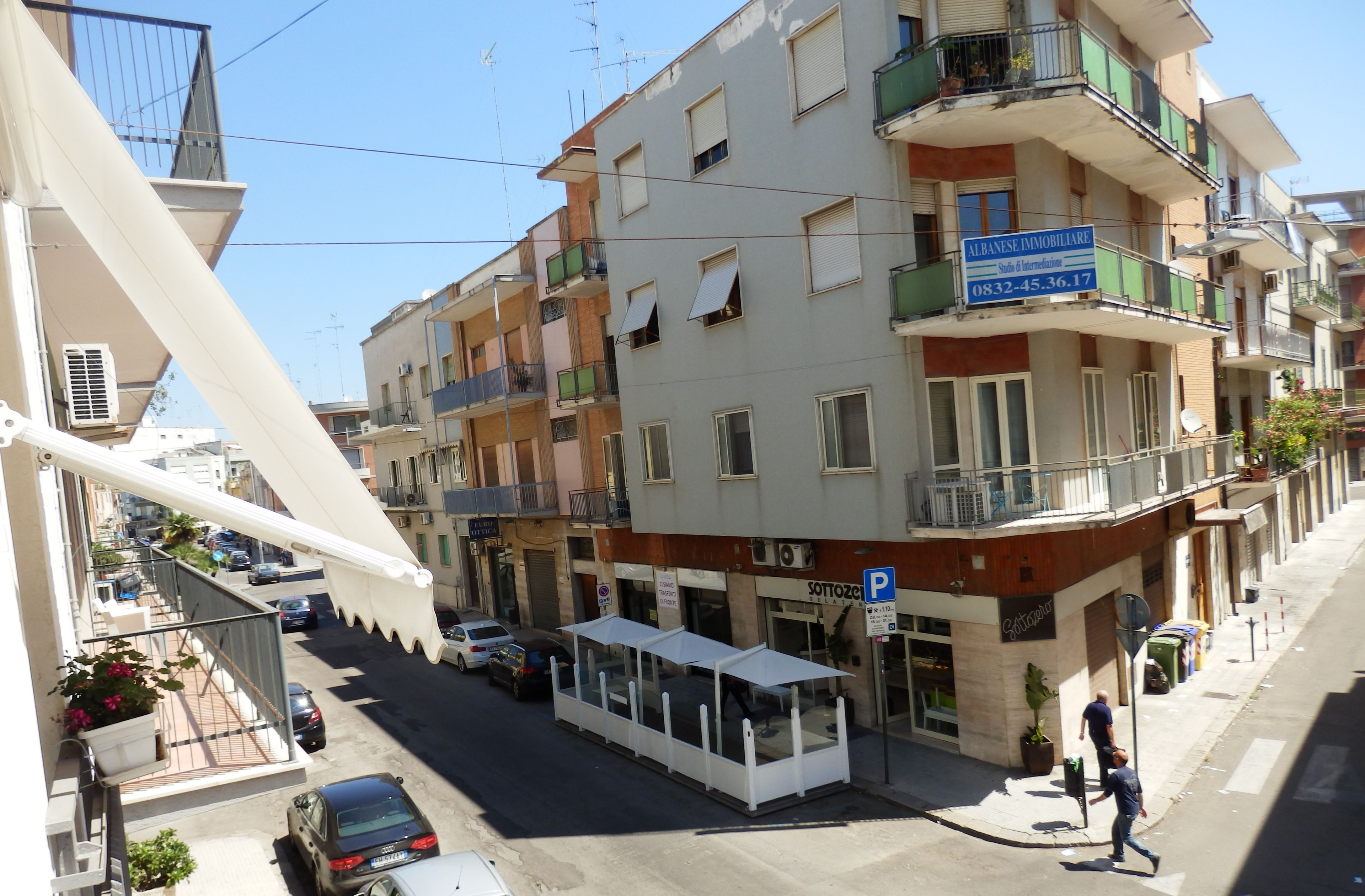 A multi-story building with balconies, a parking sign, and a storefront.